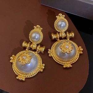 Macro shot of vintage gold floral earrings with pearls on brown leather background