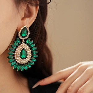 Close-up of green teardrop gems and rhinestones geometric earrings worn by model