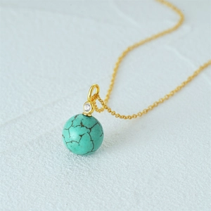 Macro shot of 925 silver necklace with spherical turquoise pendant and gold chain