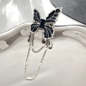 Detail of gothic black butterfly brooch with silver tassels on a metallic base