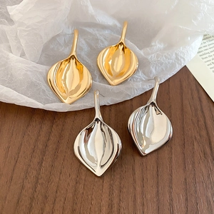 Dettaglio di eleganti orecchini a forma di foglia con finiture in oro e argento lucido