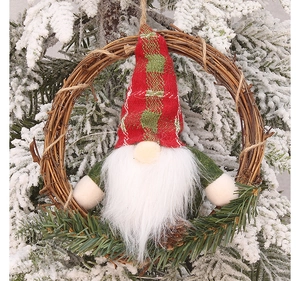 Détail d'une couronne de gnome de Noël avec bonnet à carreaux sur un sapin enneigé