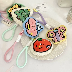 Detail of soft plush pendants with fine embroidery and woven lanyards on white plate