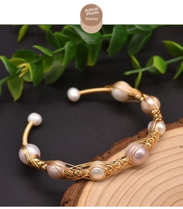 Detailed macro of handmade gold wire wrapped bracelet with white and pink freshwater pearls