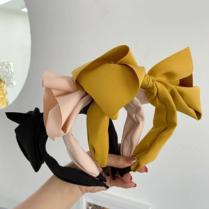 Detailed view of large bow headbands in black, soft pink, and mustard yellow fabric
