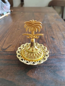 Detail of golden Middle Eastern incense burner featuring palm tree and crossed swords symbols