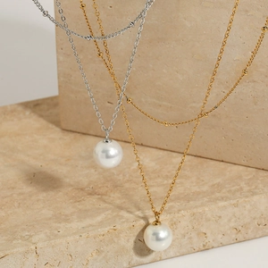 Double layer necklace with large pearl pendant in gold and silver finish on marble