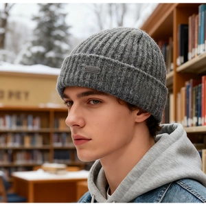 Detailed close-up of dark grey ribbed knit beanie with a metallic NY&ED engraved tag