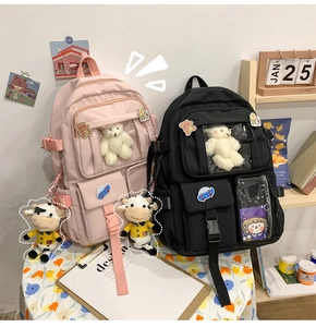 Dettaglio di zaini in nylon rosa e nero con finestre trasparenti e simpatici distintivi