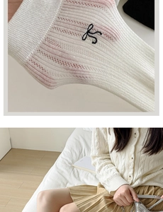 Detailed macro view of white cable knit socks with black embroidered logo design