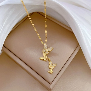 Elegant gold butterfly pendant necklace with crystal inlay on a beige jewelry box