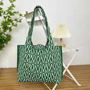 Detail of green and white patterned knit tote bag hanging on a minimalist white chair