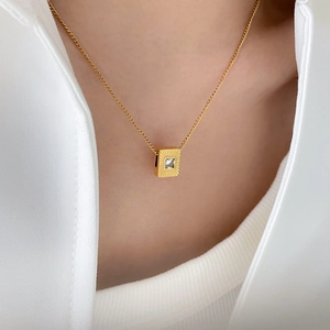 Minimalist gold necklace featuring square sunburst pendant with clear white zircon stone