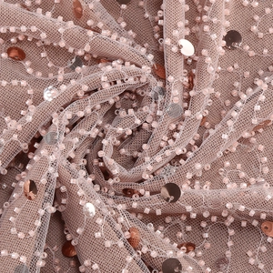 Macro detail of rose gold sequin mesh fabric with elegant beadwork and flowing lines
