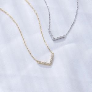 Macro shot of gold and silver V-shaped necklaces with sparkling pavé cubic zirconia details