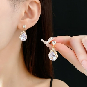 Détails de boucles d'oreilles gouttes dorées avec zircons et éclat luxueux brillant