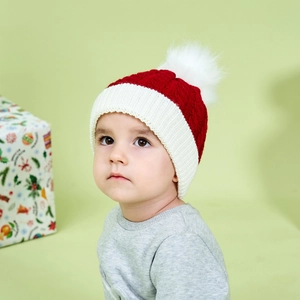 Close-up of red and white knitted winter hat with a soft white fluffy pom-pom detail