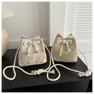 Détail du sac seau en paille tissée avec broderie délicate de fleurs de vigne vertes