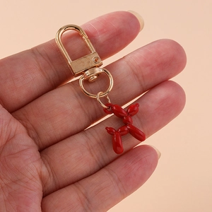 Detailed shot of a red balloon dog keychain held in hand with a gold-tone lobster clasp