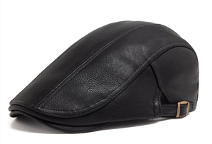 Detail view of the bronze metal adjustable buckle on a black PU leather beret cap