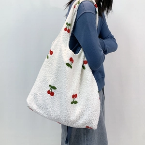 Side view of white faux shearling tote bag with cherry embroidery worn by a model
