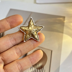 Vue macro d'une broche étoile dorée mate vintage avec motifs lune et étoiles gravés