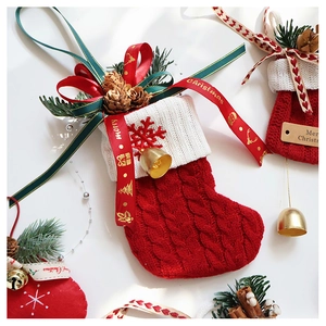 Macro detail of red knitted Christmas stockings with pine cones, cinnamon, and golden bells