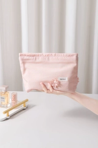 Pink and white checkered makeup bag with a 3D flower detail and fabric brand label