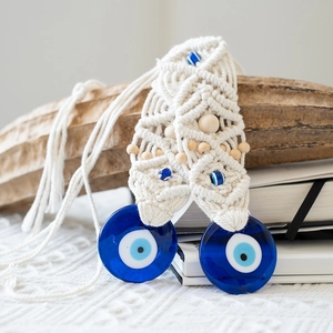 Close-up of handmade macrame Evil Eye wall hanging with blue glass beads and wood accents