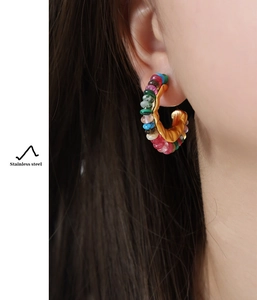 Detail of colorful beads on a vintage gold stainless steel C-shaped earring on model