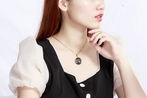 Detail of Eye of Horus pendant in gold finish worn by model with minimalist background