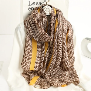 Detailed close-up of geometric pattern scarf with mustard yellow edge on white silk