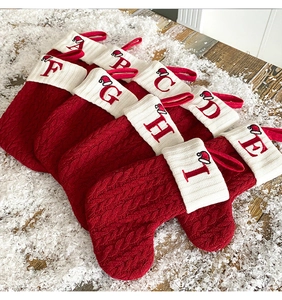 Close-up of knit Christmas stockings with alphabet embroidery on faux snow background