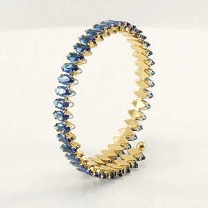 Macro view of adjustable gold-plated bangle with rows of blue marquise-cut stones