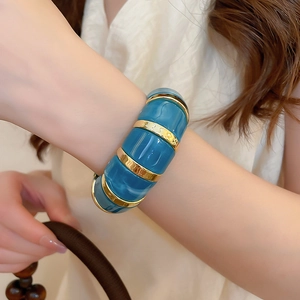 Detailed view of peacock blue marbled acrylic bracelet with gold segment accents