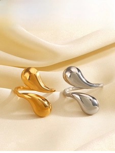 Detail of high-polished gold and silver teardrop rings on soft cream silk fabric