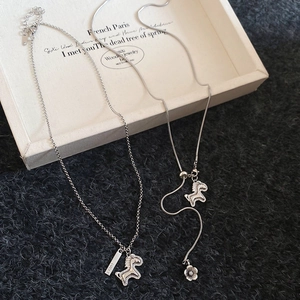 Detail of silver lucky pony pendant and floral snake chain necklace on a gift box