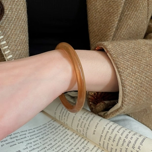 Détail d'une bague ovale en résine ambrée avec une finition lisse et brillante au doigt
