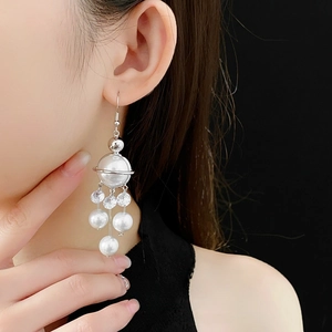 Planet pearl tassel earrings with zircon stars shown on a model against black background