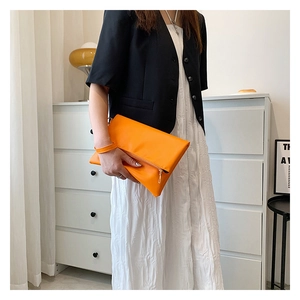 Nahaufnahme der leuchtend orangefarbenen Leder-Clutch mit Handschlaufe und Klappverschluss