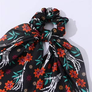 Détail d'un chouchou d'Halloween avec main de squelette et motif fleuri sur soie noire