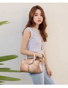Detail shot of beige faux crocodile leather tote bag with handle held by model