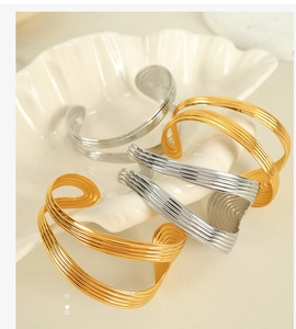 Detailed view of textured 18K gold and silver plated titanium steel open cuff bracelets