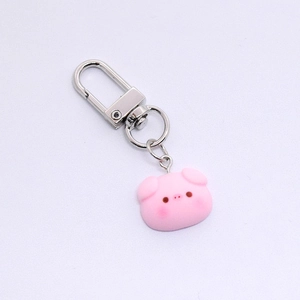 Close-up of a cute pink resin pig charm attached to a silver metal D-ring keychain