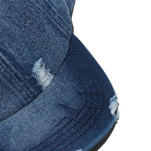 Macro view of distressed denim baseball cap showing washed details and frayed edges
