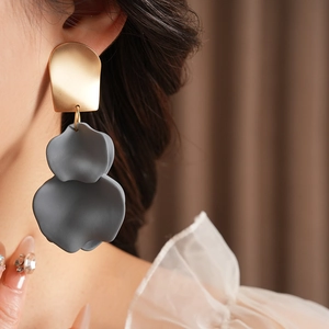 Detail of irregular grey flower petal earrings on model with golden metal accents
