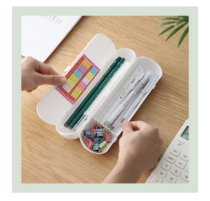 Overhead view of a white plastic multi-layer pencil box with organized stationery