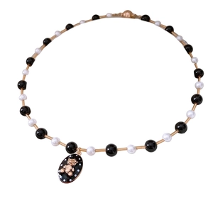 Elegant beaded necklace featuring black and white beads with a golden bear pendant accent