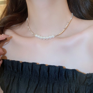 Close-up of minimalist silver chain necklace with white pearl strand on model neck