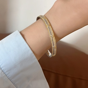 Detail of 18K gold plated two-tone cuff bracelet with cubic zirconia and texture